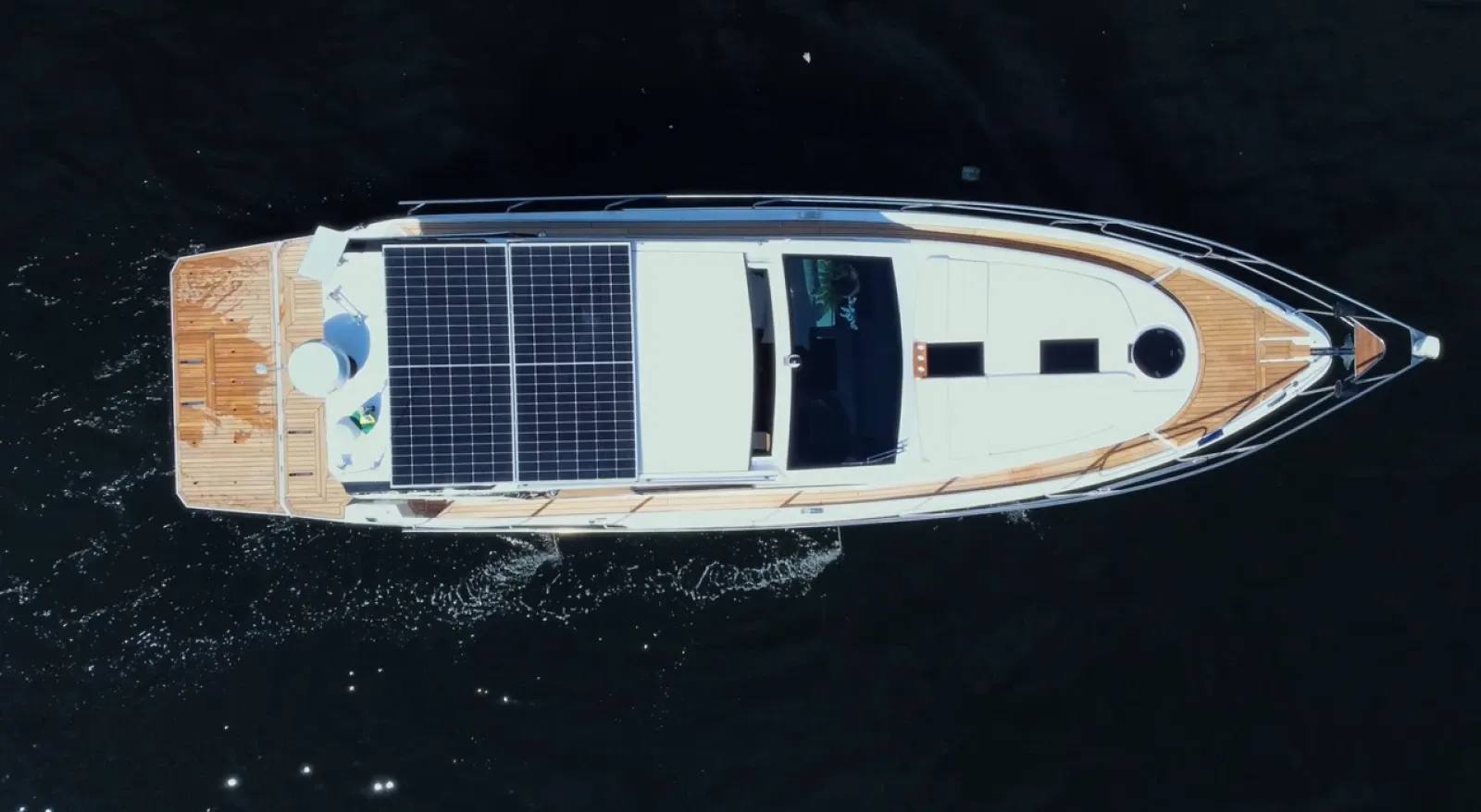 Foto aérea da lancha Coral 42 HT navegando, destacando os painéis solares instalados no teto para autonomia energética no mar