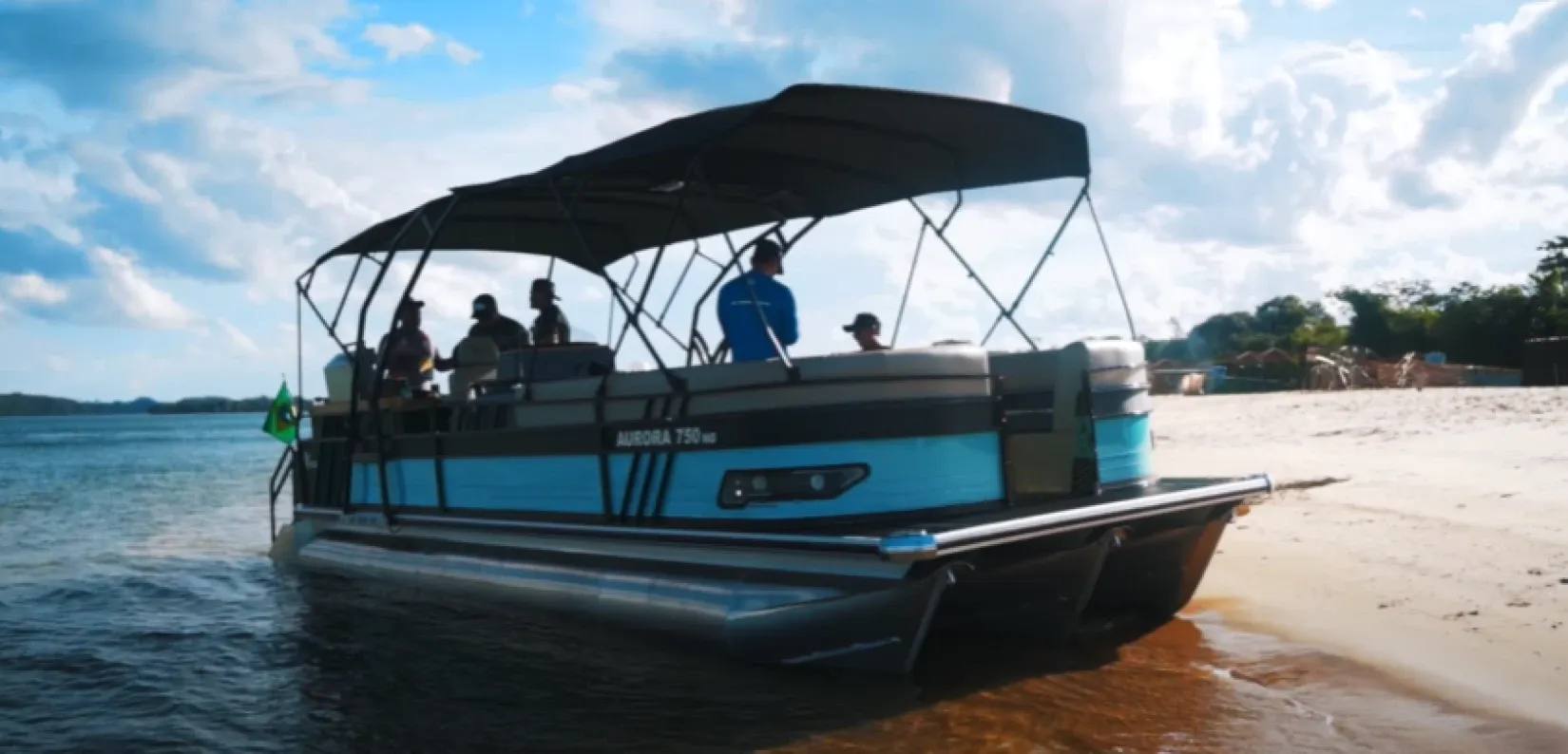 Embarcação modelo pontoon atracada na areia da praia do Cachadaço, com grupo a bordo aproveitando o passeio náutico em Porto Rico-PR.