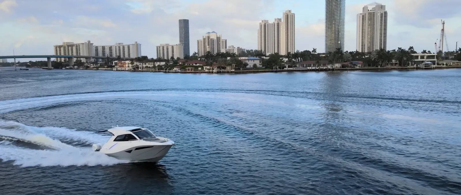 Lancha da NX Boats em alta velocidade em uma baía nos EUA, com a imponente skyline de uma cidade americana ao fundo