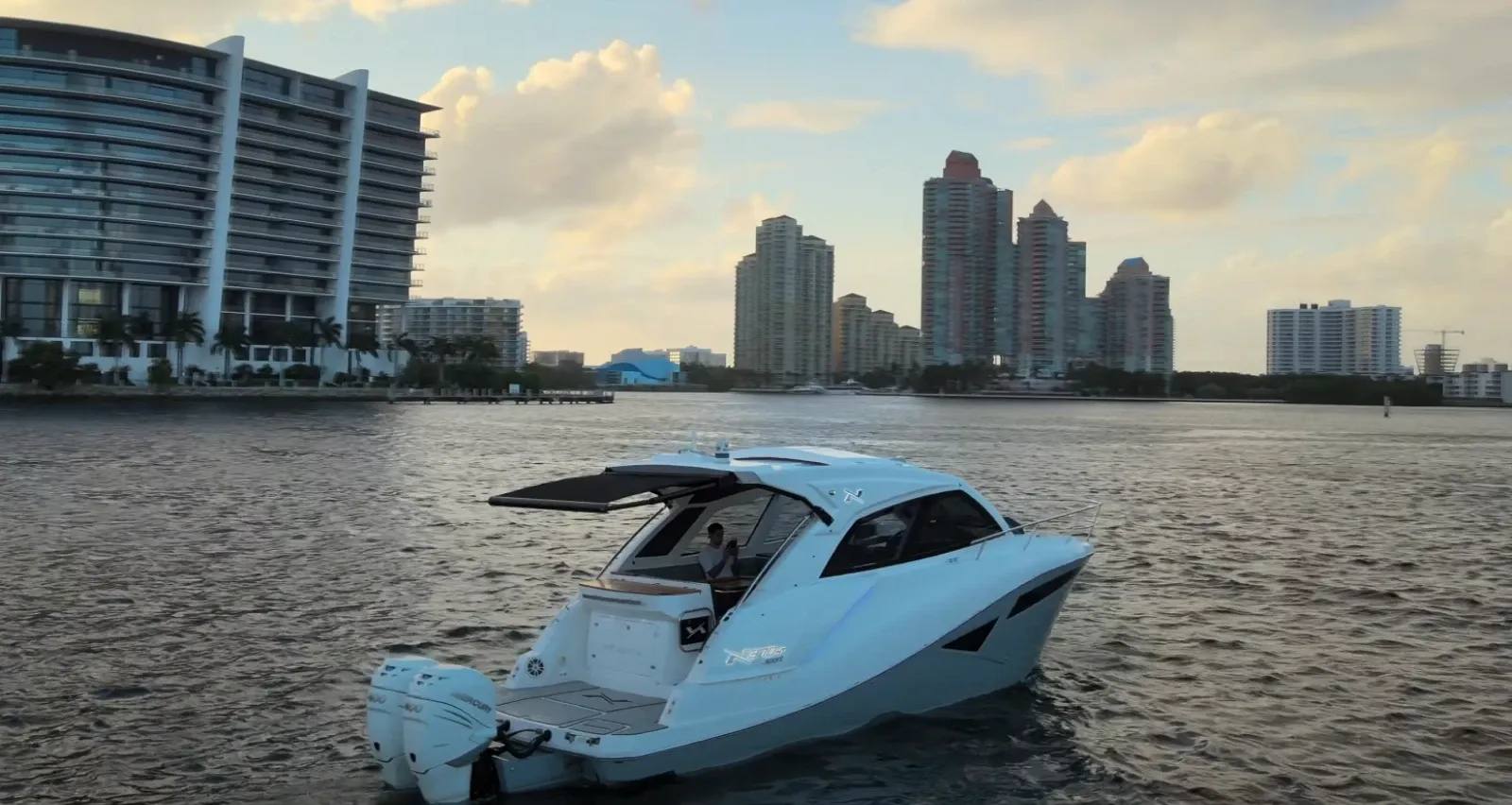 Lancha moderna com motores de popa em uma baía, com a skyline de Miami ao fundo durante o pôr do sol, ilustrando as vantagens de design e desempenho